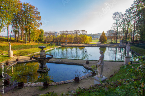 Idyllic landscape in Domaine national de Saint-Cloud - awe park and pond with statues at autumn . Golden and red colors of autumn in Paris!