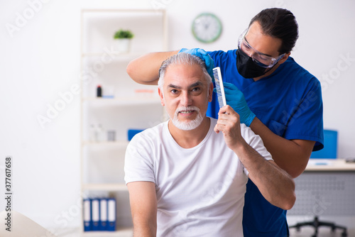Old man visiting young male doctor in hair transplantation conce