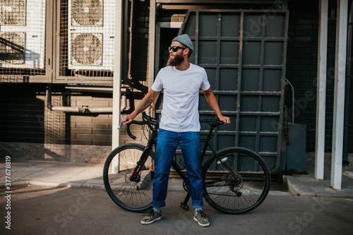 Young bearded hipster guy wearing white blank t-shirt with bicycle . Mock-up for print. T-shirt template.