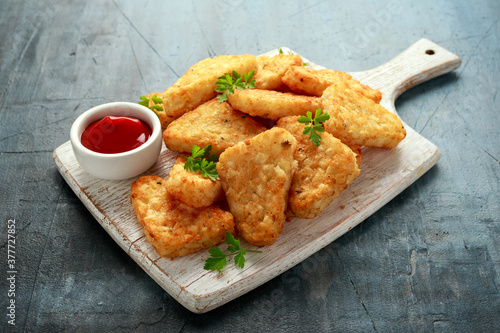 Hash brown potato with ketchup on white wooden board