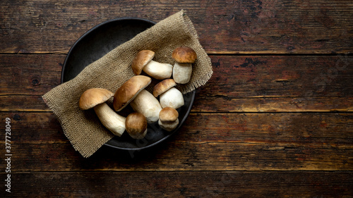 Fresh forest mushrooms /Boletus edulis (king bolete) / penny bun / cep / porcini in an old bowl / plate on the wooden dark brown table, top view background