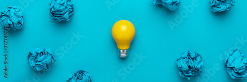 New idea concept with crumpled office paper and light bulb. Top view of great business idea concept over blue background. Creative solution during brainstorming session concept.