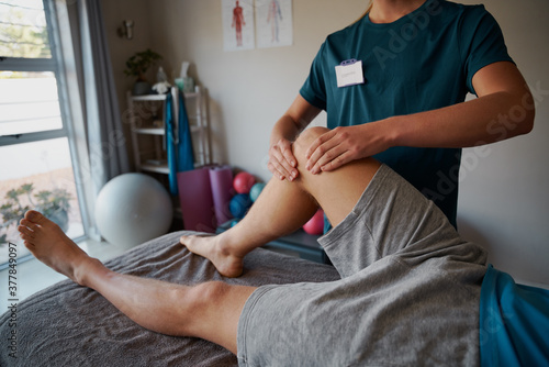 Closeup of young female physiotherapist hands giving leg exercise to patient in clinic