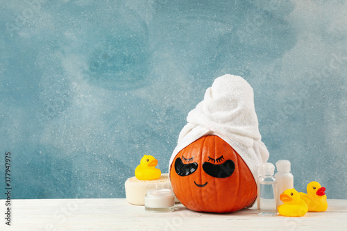 Skincare accessories and pumpkin with eye patches on blue background