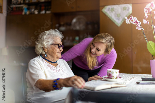 Young woman spending time with her elderly grandmother at home 