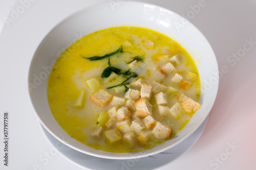 A white plate with cheese soup with rusks