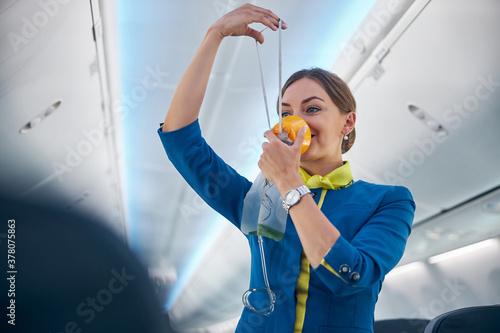 Air hostess showing how to use an oxygen mask on board