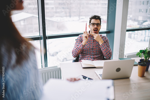 Amazed Caucasian professional employer classic eyewear impressed with received information during interview questionnaire, shocked man listening recruitment presentation from cropped female trainee