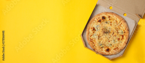 Cheese pizza in carton box on yellow background