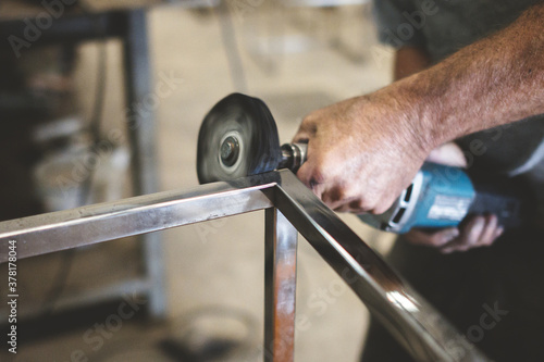 Closeup of a person polishing steel under the lights in a garage