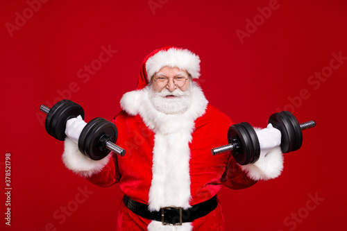 Photo of pensioner old man grey beard hold lift two dumbbells confident sportive grandpa training wear costume leather belt gloves coat spectacles headwear isolated red color background