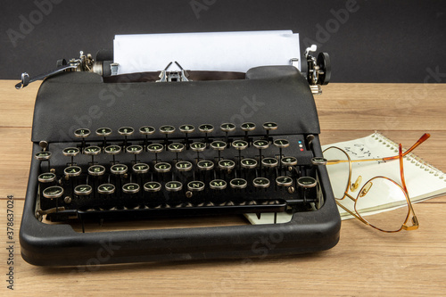 an old black portable typewriter with a steno pad and eye glasses as at a secretary's desk