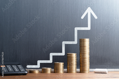 Financial growth and investment progress. Stack of coins and calculator. Steps and arrow drawn on blackboard.