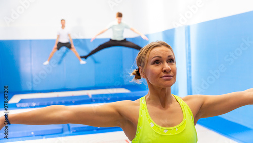 Close-up portrait of young female gymnast during trampoline workout in modern fitness center
