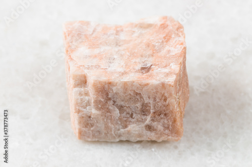 closeup of sample of natural mineral from geological collection - unpolished Feldspar rock on white marble background