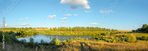 Summer panoramic landscape with calm lake and forest during sunset