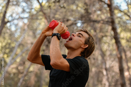 Person drink water of his bottle in the forest