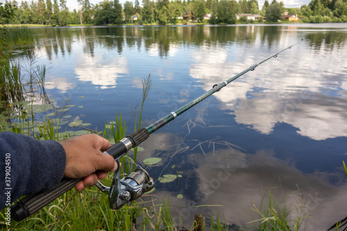 Hand with a fishing rod on a forest lake