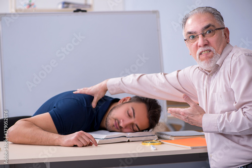 Old teacher and young male student in the classroom