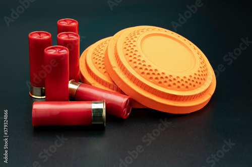 Clay disc flying targets and shotgun bullets on black background ,Clay Pigeon target