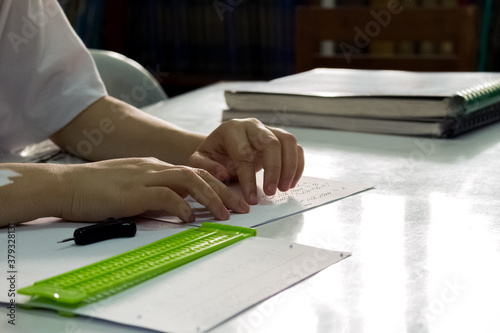 Hand touching braille text with slate and stylus , Education for blind people.