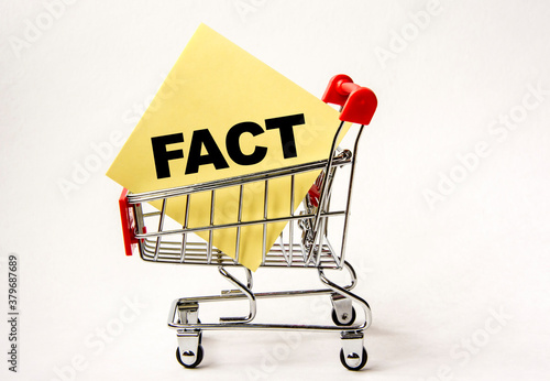 Shopping cart and text fact on yellow paper note list. Shopping list, business concept on white background.