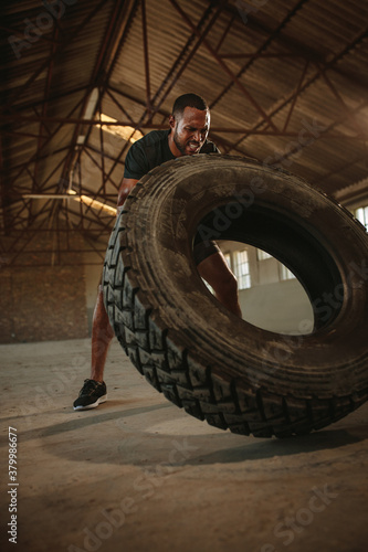 Man doing tire flipping workout at empty warehouse