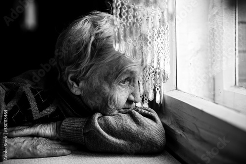 An old woman looking at the window. Black and white photography.