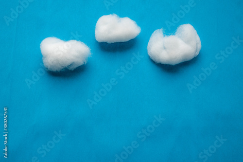 Clouds on blue sky reproduction using white cotton wool on blue creped paper background.