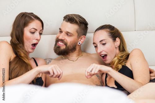 couple having threesome fun in bed with another woman