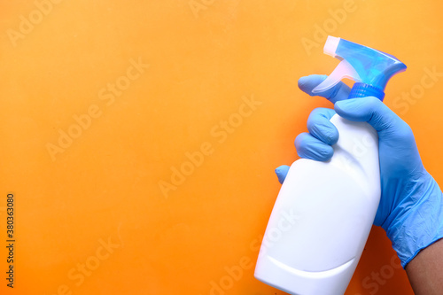 Person hand in disposable gloves holding disinfectant spray