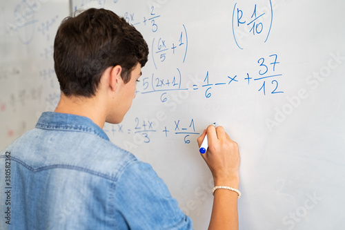 College student solving math equation on white board