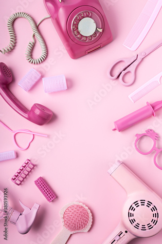 Creative layout made of hair dryer, scissors and accessories on pink background. Retro vintage 70's and 80's aesthetic with summer shadows. Flat lay, copy space, top view.