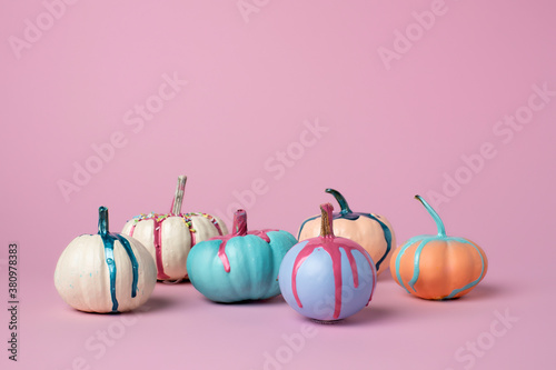 Autumn layout made of colorful pumpkins with dripping paint on pink background. Minimal Fall or Halloween concept.