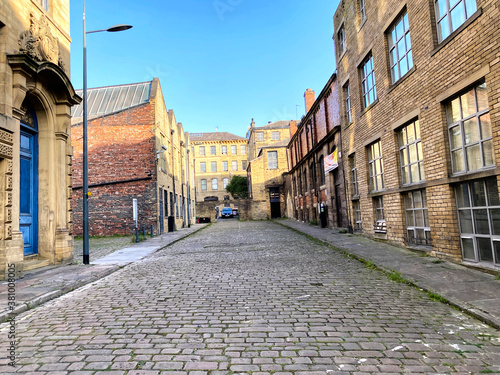 Looking up, the old cobbled stone Burnett Street, lined with former textile mills in, Little Germany, Bradford, UK