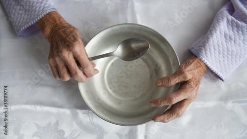 View from above.The hands of an old grandmother of 90 years are holding an empty aluminum bowl and spoon, poverty and poverty, the hunger of the older generation. 