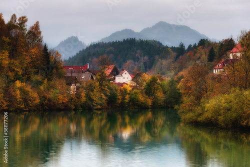Wonderful landscape of mountain village in fall. View of forest with yellowed foliage, which reflects in water. Fussen. Lech river. Bavaria. Germany.
