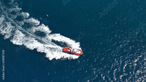 Aerial drone photo of red pilot boat cruising in high speed in Mediterranean deep blue sea offering navigational aid to ships
