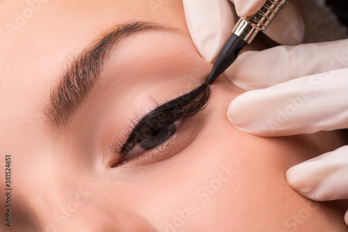 Permanent eye makeup close up shot. Cosmetologist applying tattooing of eyes. Makeup eyeliner procedure