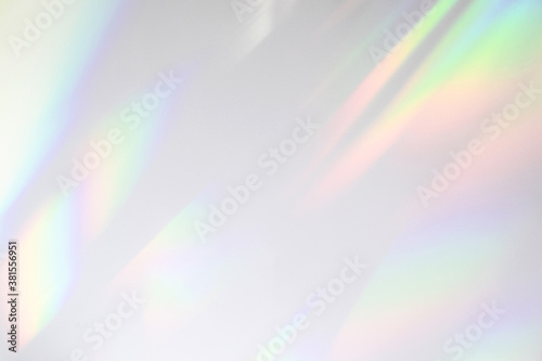 Blurred rainbow light refraction texture overlay effect for photo and mockups. Organic drop diagonal holographic flare on a white wall. Shadows for natural light effects