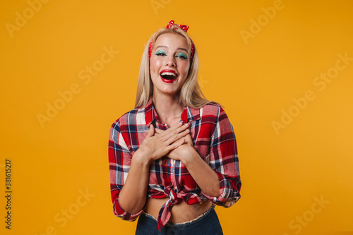 Image of joyful beautiful pinup girl posing with hands on her chest