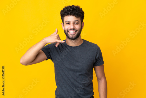 Young Moroccan man isolated on yellow background making phone gesture. Call me back sign