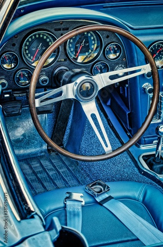 Vertical: Driver's side view of blue, classic, vintage convertible car with wooden and chrome steering wheel 