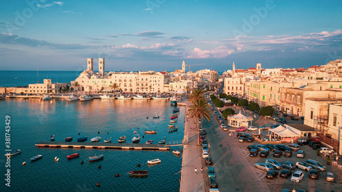 Beautiful panoramic aerial view photo from flying drone on Molfetta waterfront with the Old Cathedral San Corrado (Duomo Vecchio),port with ships and yachtsand the Molfetta city sunset. Apulia ,Italy