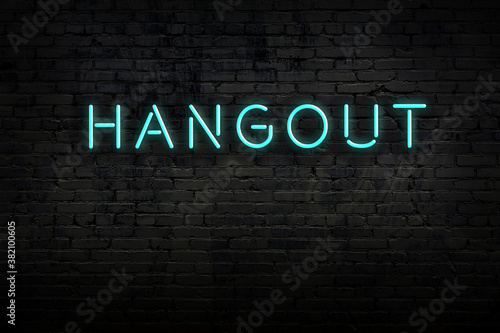 Night view of neon sign on brick wall with inscription hangout