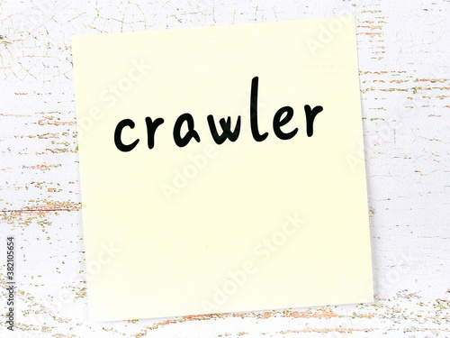 Yellow sticky note on wooden wall with handwritten word crawler