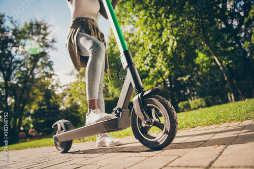 Cropped view of her she teenage teen trendy skinny slim fit hipster girl's legs riding kick scooter spending free time sunny day having fun activity sport in forest wood outdoor youth hobby