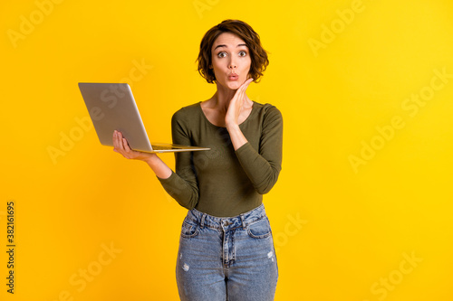 Photo of astonished lady hold laptop touch face with hand isolated over vivid yellow color background