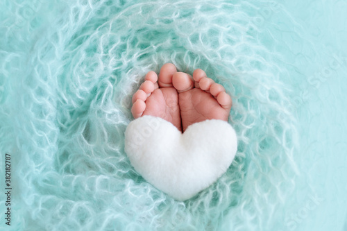 legs newborn baby close up on a blue background with a toy in the form of a heart