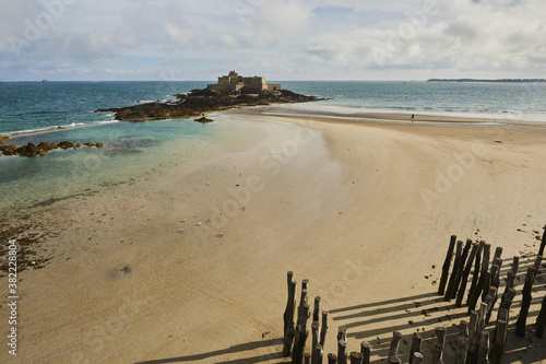 Wooden Poles et Fort National on the beach at low tide in Saint Malo, Brittany, France